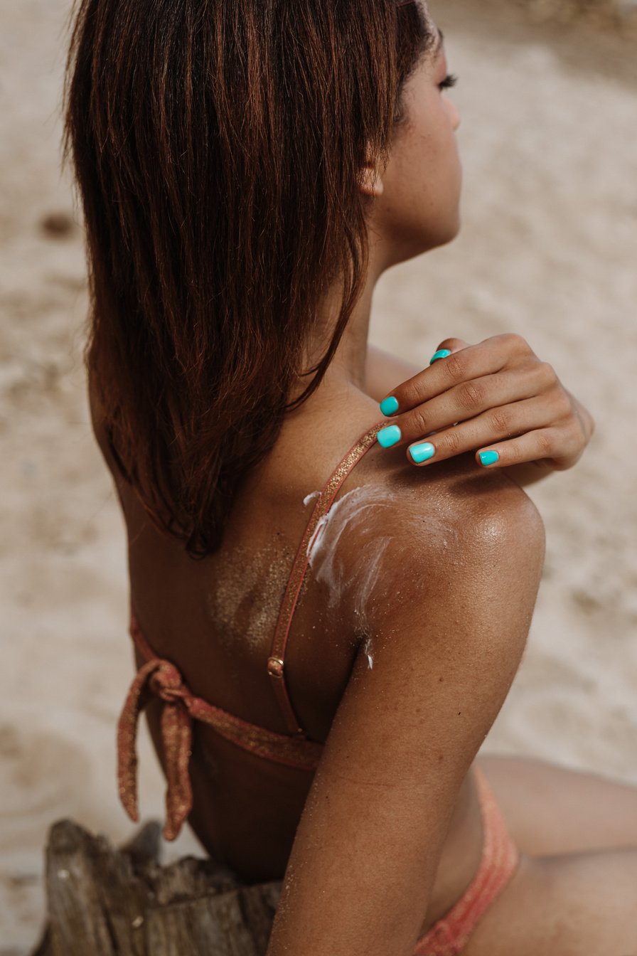 Woman Putting Sunblock on Back 